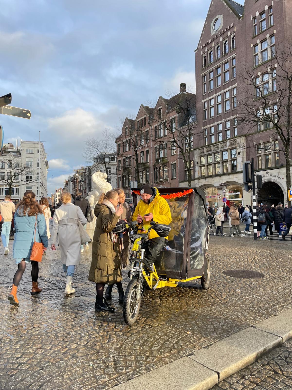 Een gesprek op straat bij een fietstaxi op de Dam in Amsterdam